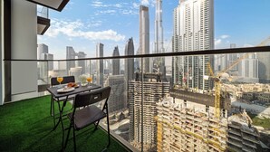 A balcony with a table and chairs, offering a view of a cityscape with high-rise buildings and construction cranes. - Delujo Stays – Burj Crown Collection (Dubai)