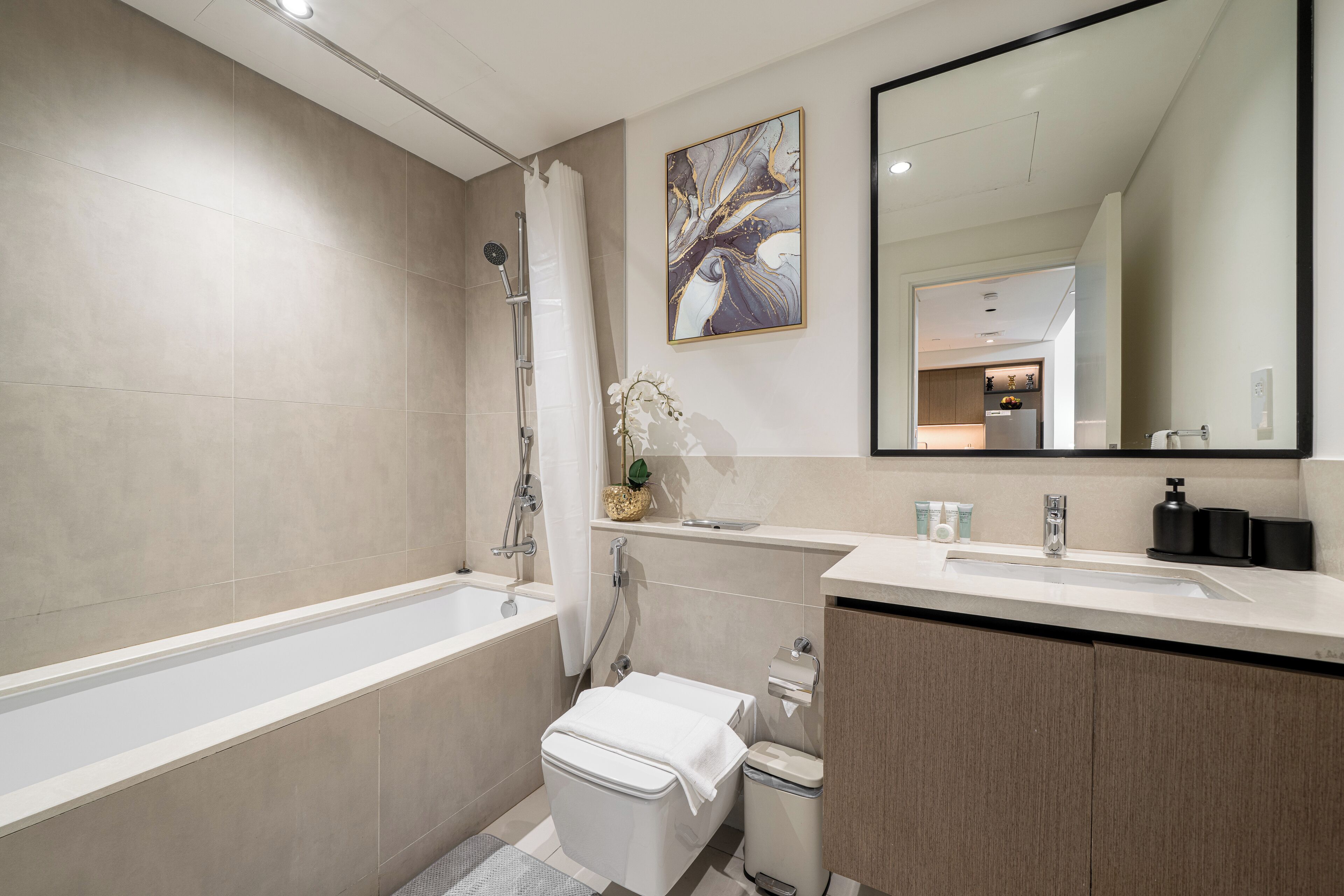 A modern bathroom with a bathtub, toilet, sink, and mirror.