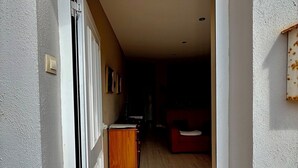 A hallway with a wooden cabinet, a red sofa, and a tiled floor. - Apartamento Torreblanca III Ref 063 (Torreblanca)
