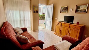 A living room with a sofa, a TV, and a wooden cabinet. - Apartamento Torreblanca III Ref 063 (Torreblanca)
