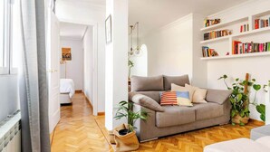 Un salon avec un canapé, une bibliothèque et une plante en pot.