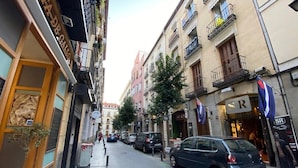Une rue étroite, bordée de voitures garées et d’immeubles des deux côtés.