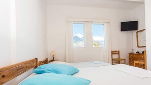 A hotel room with two beds, a TV, a wooden dresser, and a window with a mountain view. - Bluewhite Studio - Mountain View by the Pool (Kefalonia)