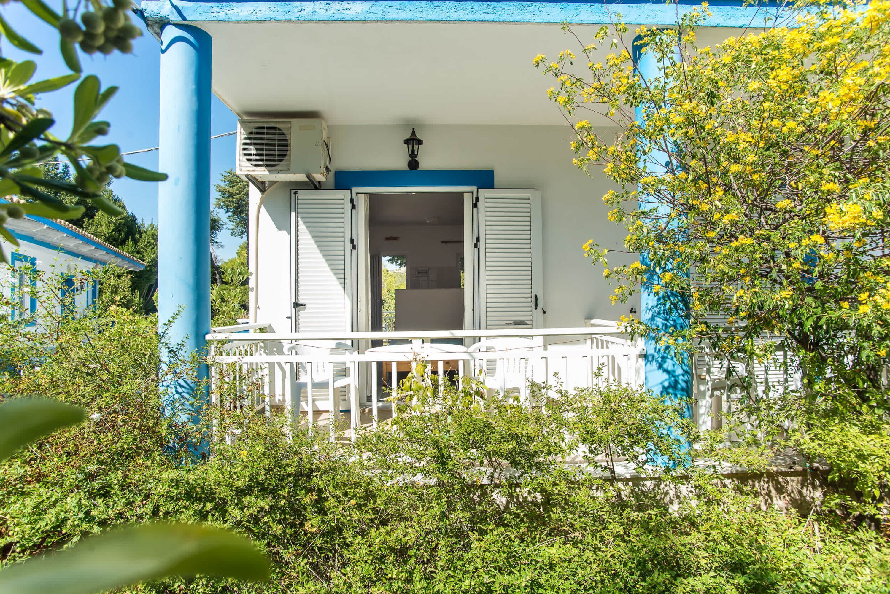 A house with a balcony, white shutters, and a blue door.