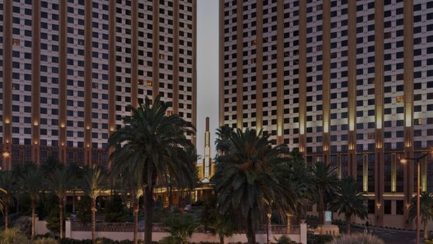 A high-rise building with a grid-like facade, multiple floors, and a central vertical feature.