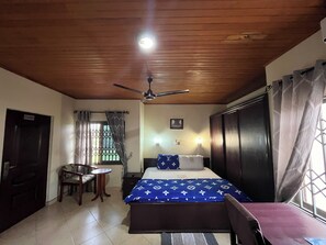 A bedroom with a bed, a desk, a chair, a ceiling fan, and a window with curtains. - My view guest house (Ejisu)