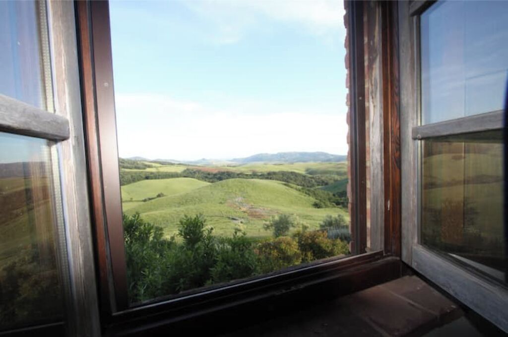 Une fenêtre donnant sur des collines verdoyantes et des montagnes lointaines.