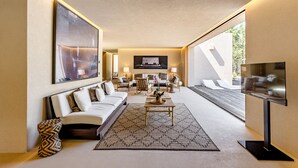 A modern living room with a sofa, coffee table, and TV. There is a large window providing natural light and a view of the outdoors. - Melides Premium Villa With Pool by Homing (Grandola)