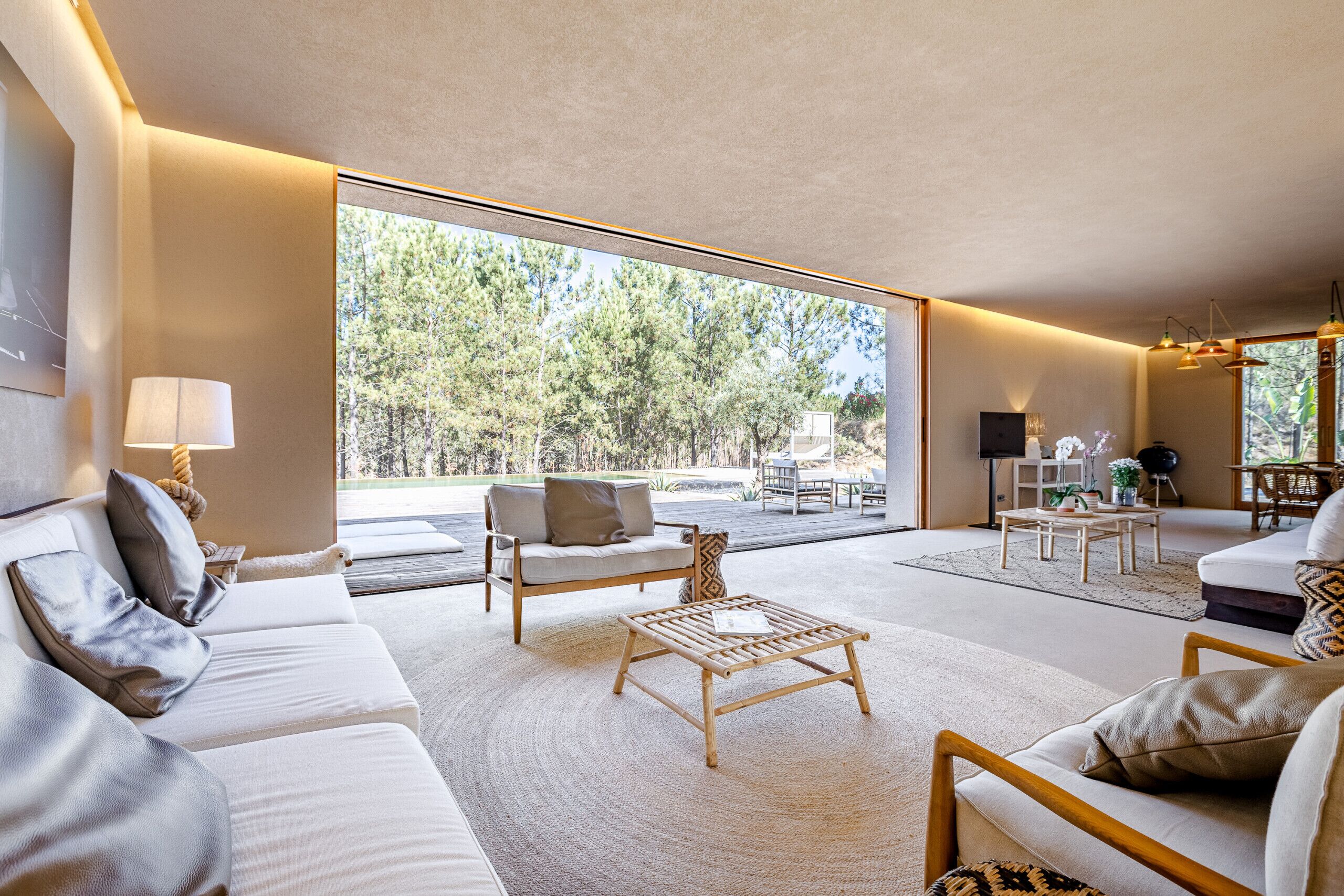 A spacious living room with a large window, a sofa, a coffee table, and a dining area.