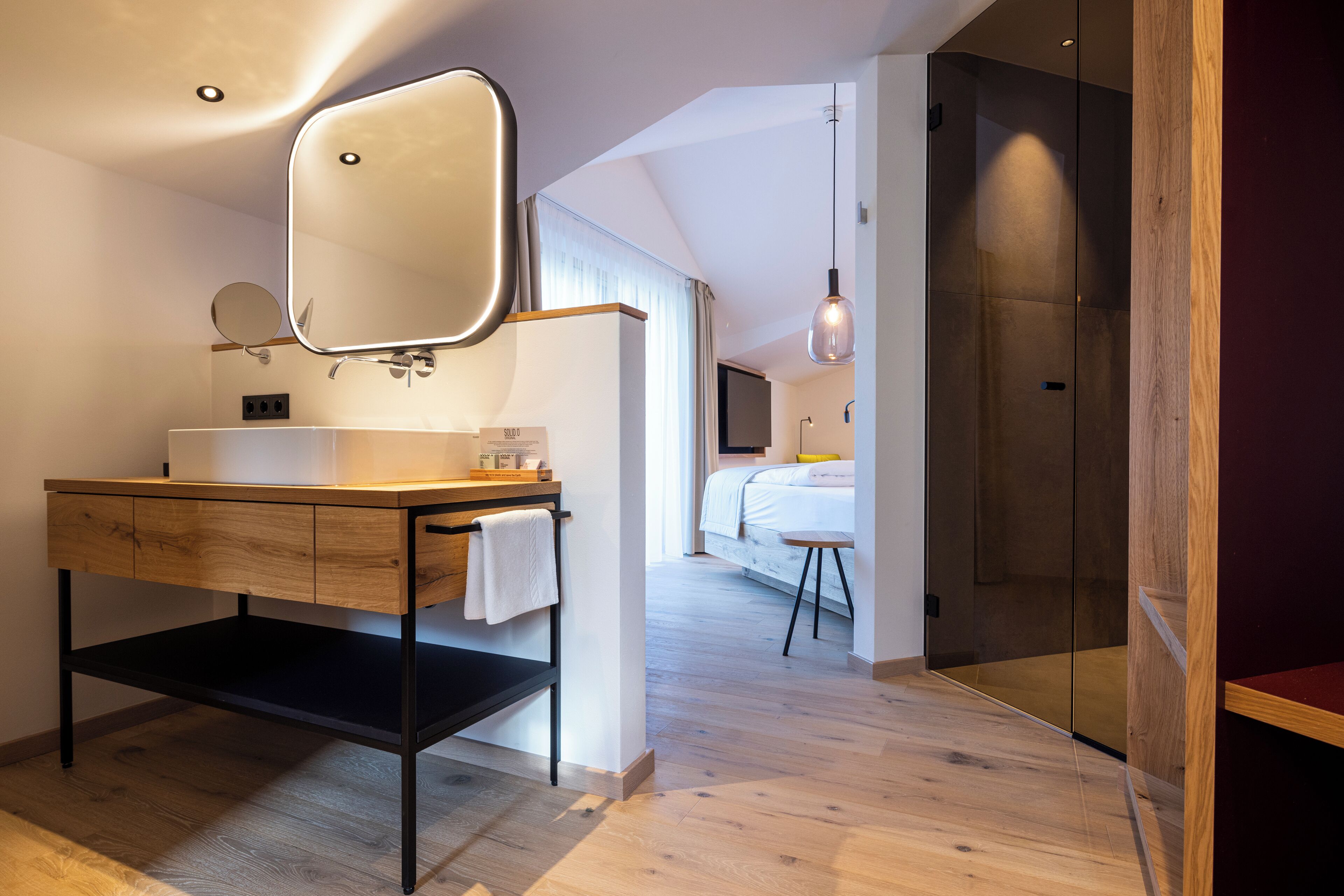 Un bagno moderno con un mobile vanitario in legno, uno specchio grande e un angolo doccia.