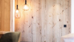 A wooden wall with two hanging pendant lights and a bench. - Hotel Baumwirt (Castelrotto)