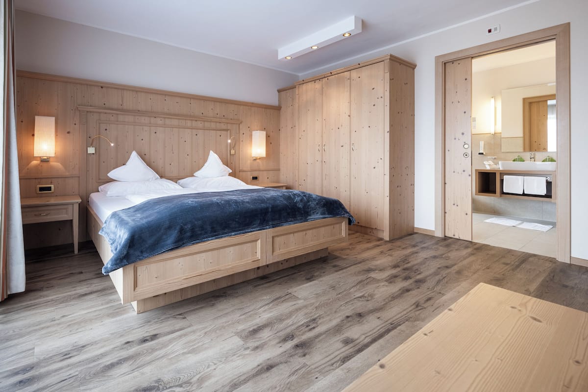 A modern bedroom with a wooden bed, bedside tables, and a wardrobe.