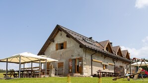 Un bâtiment de style rustique, doté d’un toit en pente, de poutres en bois et d’un espace extérieur abrité avec des sièges.
