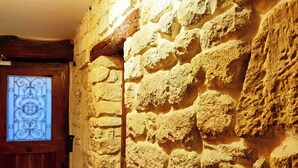Una pared de piedra con una puerta de madera y un ventanal decorativo.