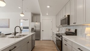 Une cuisine moderne avec des meubles blancs, des appareils en acier inoxydable et un îlot central.