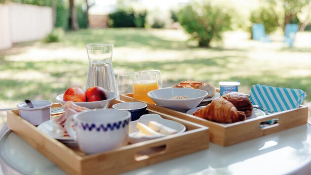 A breakfast tray with croissants, fruits, and beverages on a table outdoors. - Le Clos des Pies, Triple room "Le Nid", quiet and green in the Jura mountains (Le Pin)