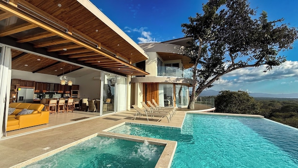 A modern house with a large swimming pool, a dining area, and a kitchen.