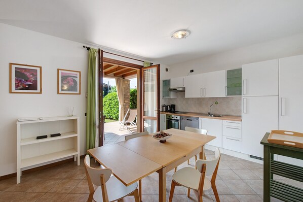 A modern kitchen with white cabinets, a wooden table, and a dining area.
