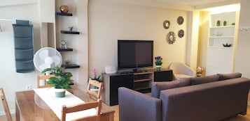 Ein Wohnzimmer mit Fernseher, Sofa, Esstisch, Stühlen und Dekoration.