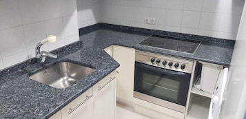 Eine Küche mit Granitabdeckung, Edelstahl-Spüle und eingebautem Backofen.