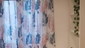 A room with a floral-patterned curtain, a white desk, and a plant on the wall. - Rooms San Marcos (Madrid)