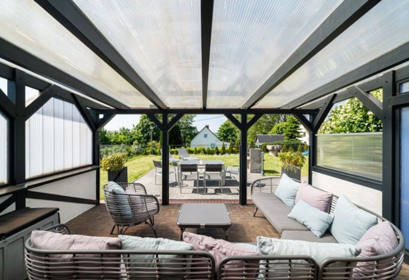 Eine Terrasse im Freien mit überdachtem Sitzbereich, einem Tisch und Stühlen.
