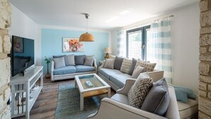 A living room with a sofa set, a coffee table, a TV, and a stone wall.