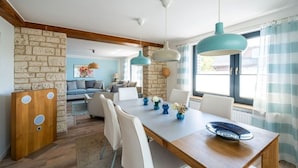 A dining area with a wooden table, white chairs, and blue pendant lights.