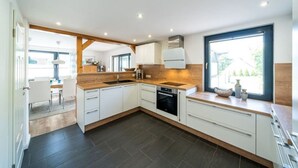 A modern kitchen with white cabinets, a black oven, and a large window.