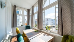 A dining area with a table, chairs, and a view of the city through large windows. - Villa Meeresgold `Strandidyll` Premium Suite (Binz)