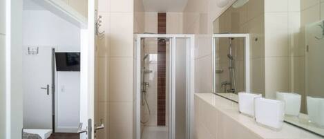 A modern bathroom with a large mirror, a sink, and a shower area.