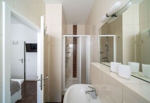 A modern bathroom with a large mirror, a sink, and a shower area. - Villa Meeresgold `Strandidyll` Premium Suite (Binz)