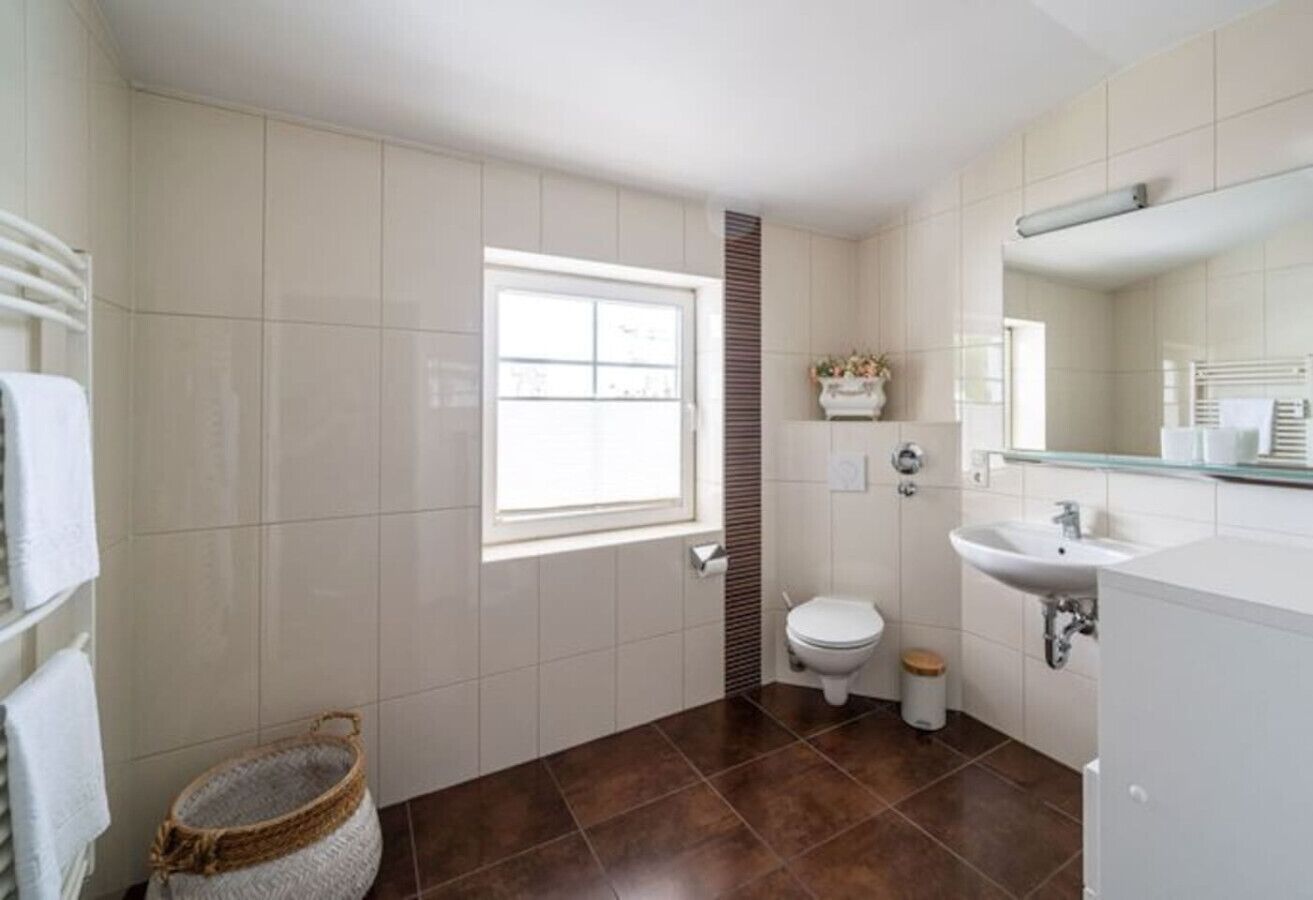 Une salle de bain avec des toilettes, un lavabo et une fenêtre.