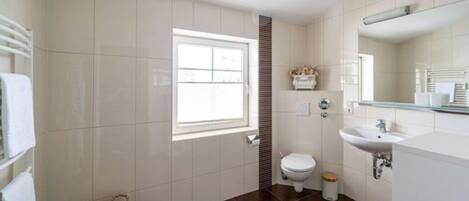 Une salle de bain avec des toilettes, un lavabo et une fenêtre.