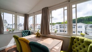 A bright room with a large window, a table, and two chairs. - Villa Meeresgold "Sea View" Premium Suite (Binz)