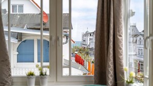 A room with a view of a street, a window with curtains, and a green chair. - Villa Meeresgold "Sea View" Premium Suite (Binz)