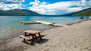 Een helder meer met een houten picknicktafel en een steiger die in het water reikt.
