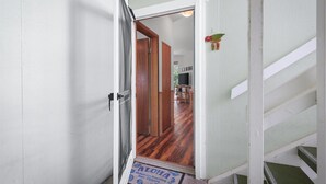 Un couloir au plancher de bois menant à une pièce dotée d’une porte.