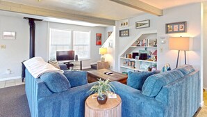 A living room with a blue sofa set, a coffee table with a plant, a TV, and a bookshelf.