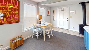 A room with a table and chairs, a window with blinds, a door, and a black stove.