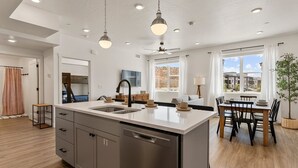 A modern kitchen with a large island, stainless steel appliances, and a dining area with a table and chairs. - Comfort At Cliff Side 2 Bedroom Condo (Hurricane)