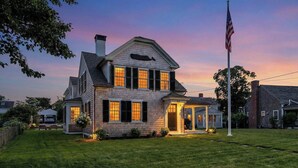 A two-story house with a porch, a garage, and a flagpole.