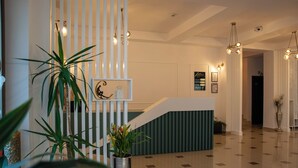 Een receptiegedeelte met een receptiebalie, potplanten en een trap naar de bovenverdiepingen.