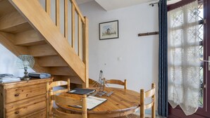 Ein Holztisch mit Stühlen, eine Holztreppe und eine Tür mit einer Spitzenvorhang.