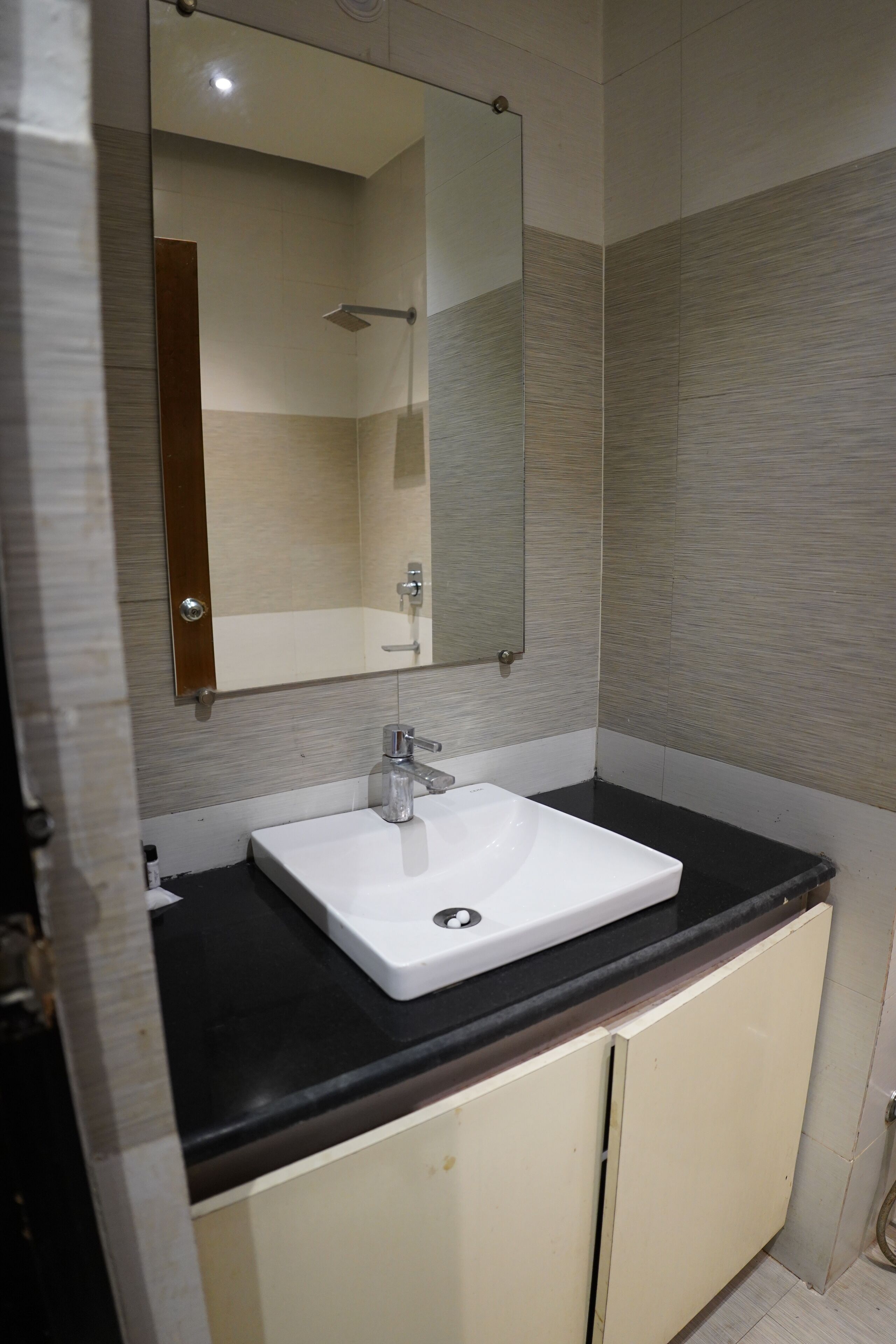 Un baño con un lavamanos blanco, un espejo y armarios color beige.