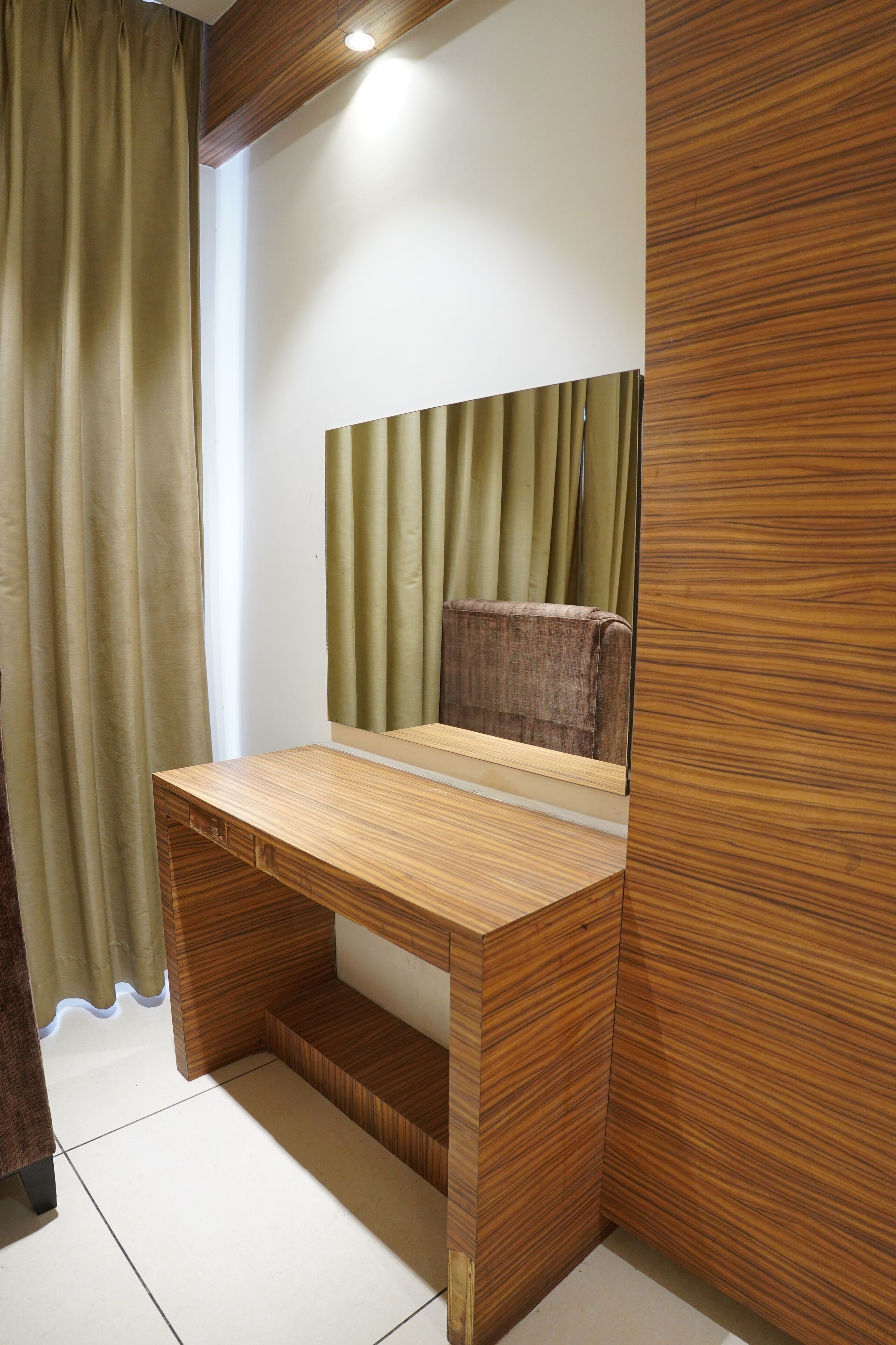 A modern room with a wooden desk, a mirror, and a window with curtains.
