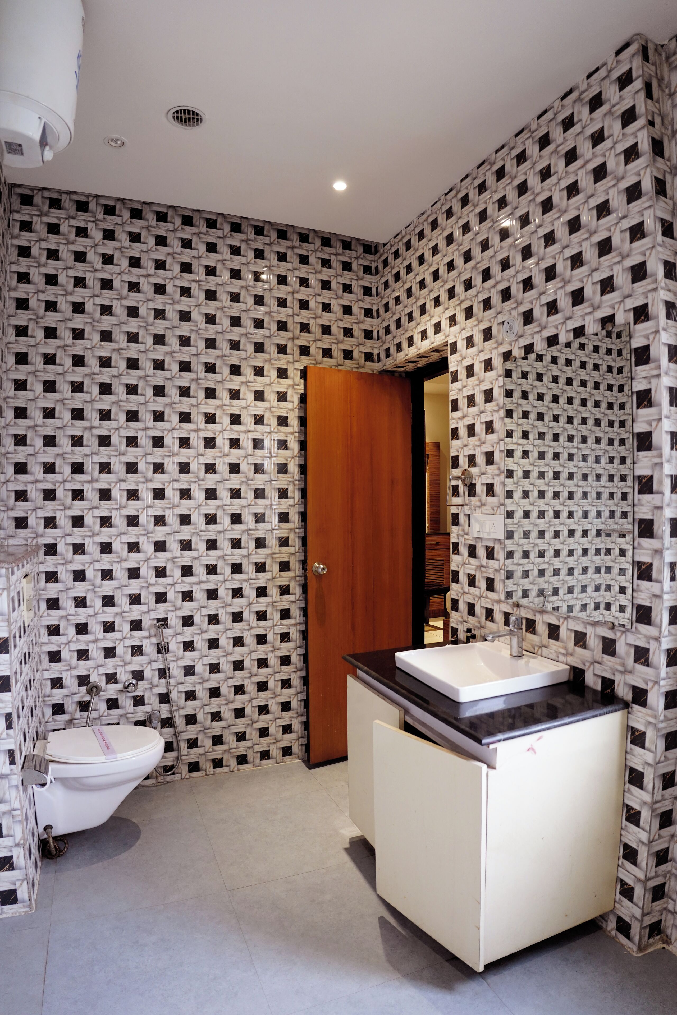 A bathroom with a patterned wall, a toilet, a sink, and a mirror.