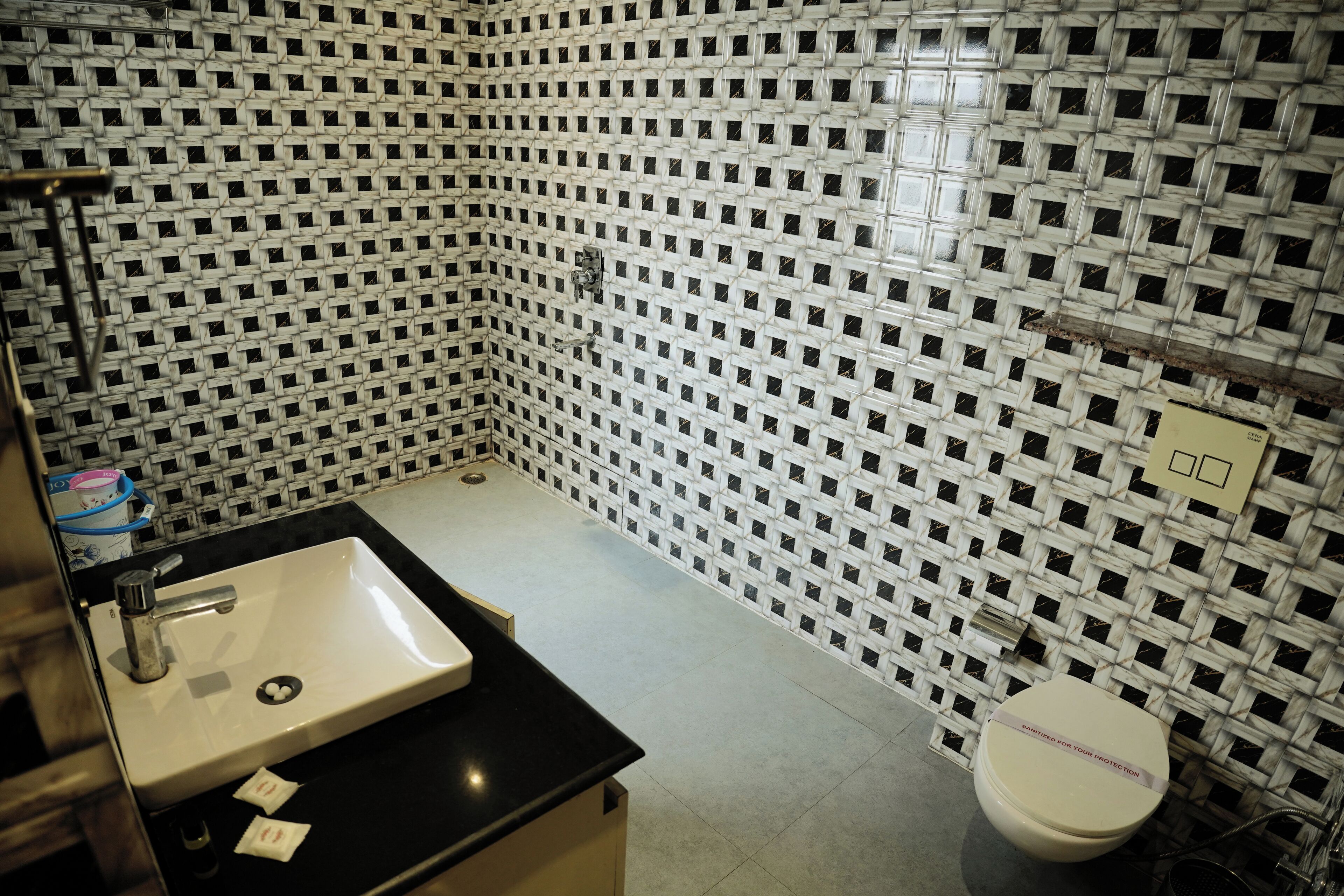 A bathroom with a sink, mirror, and toilet. The walls are covered with a black and white checkered pattern.