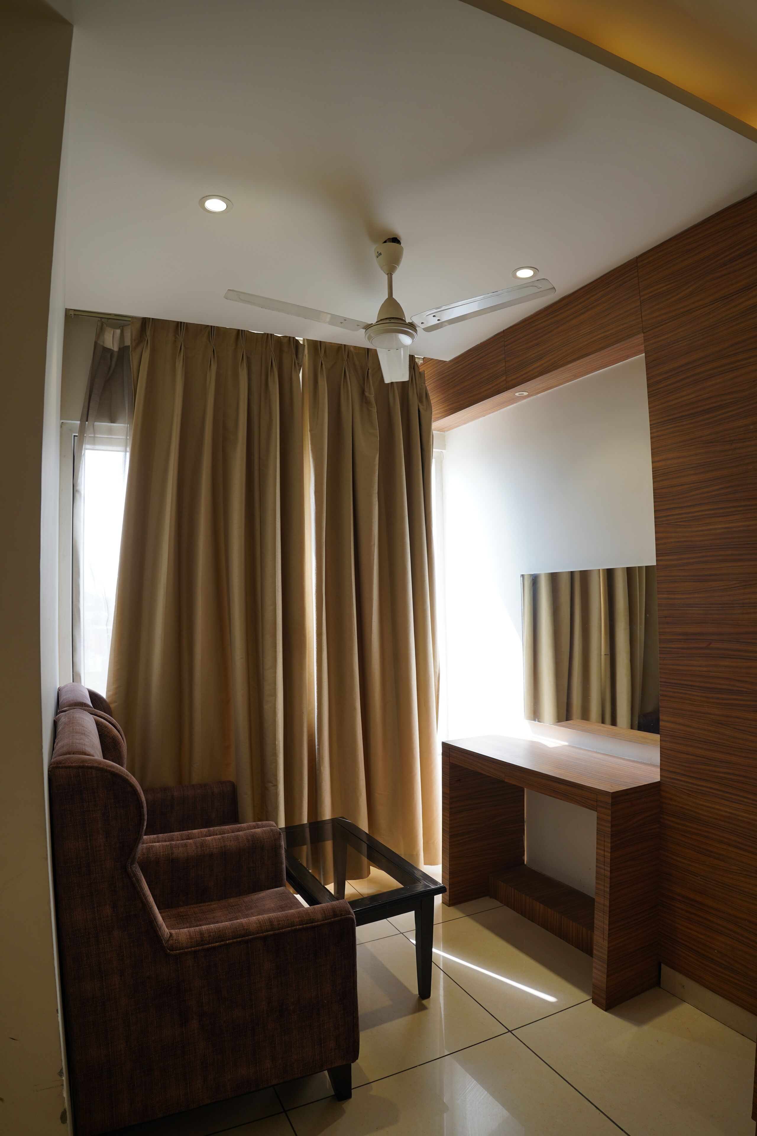 A modern living room with a sofa, a coffee table, a ceiling fan, and a large window with curtains.