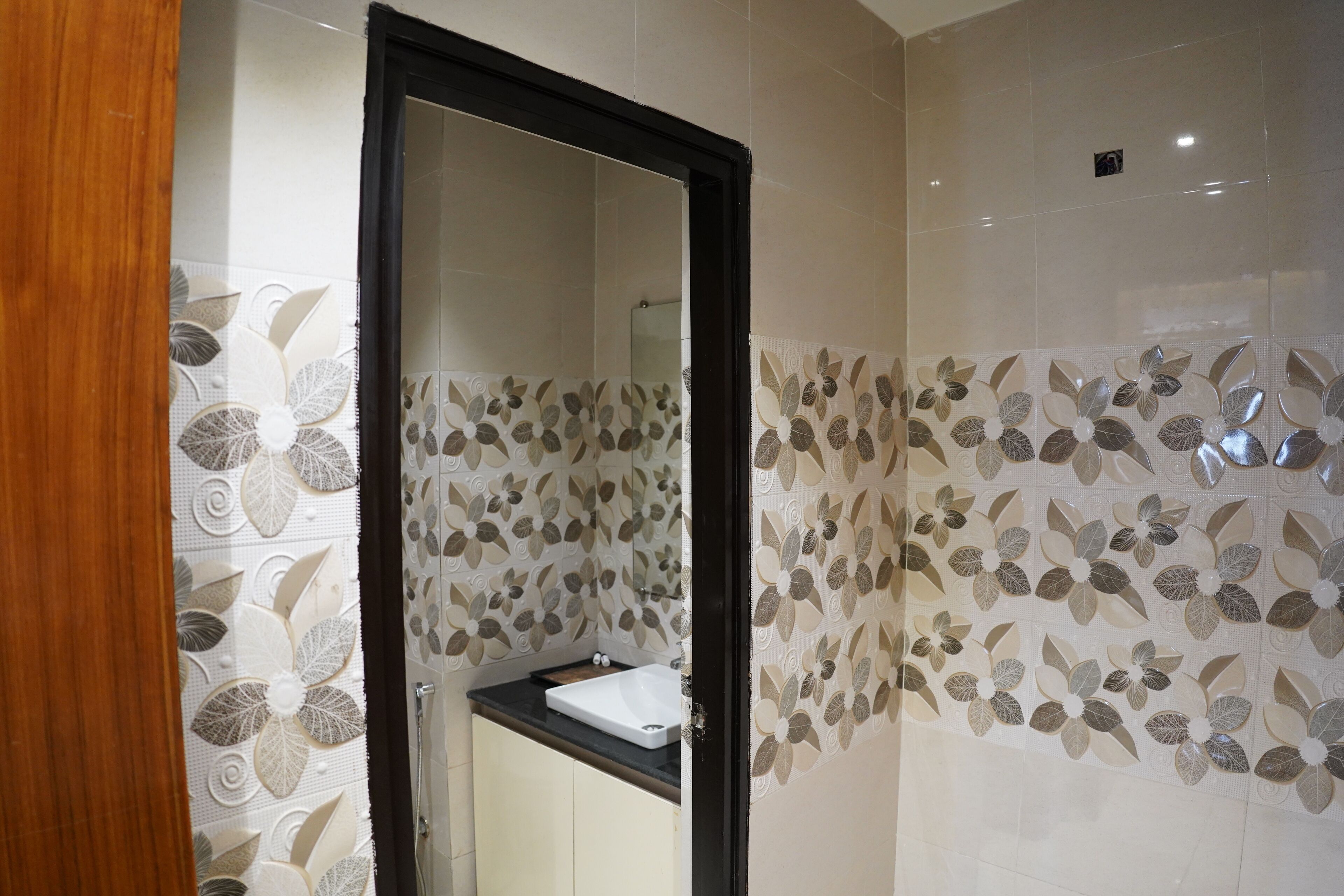 Une salle de bain avec un miroir, un lavabo et des carreaux muraux décoratifs à motifs floraux.